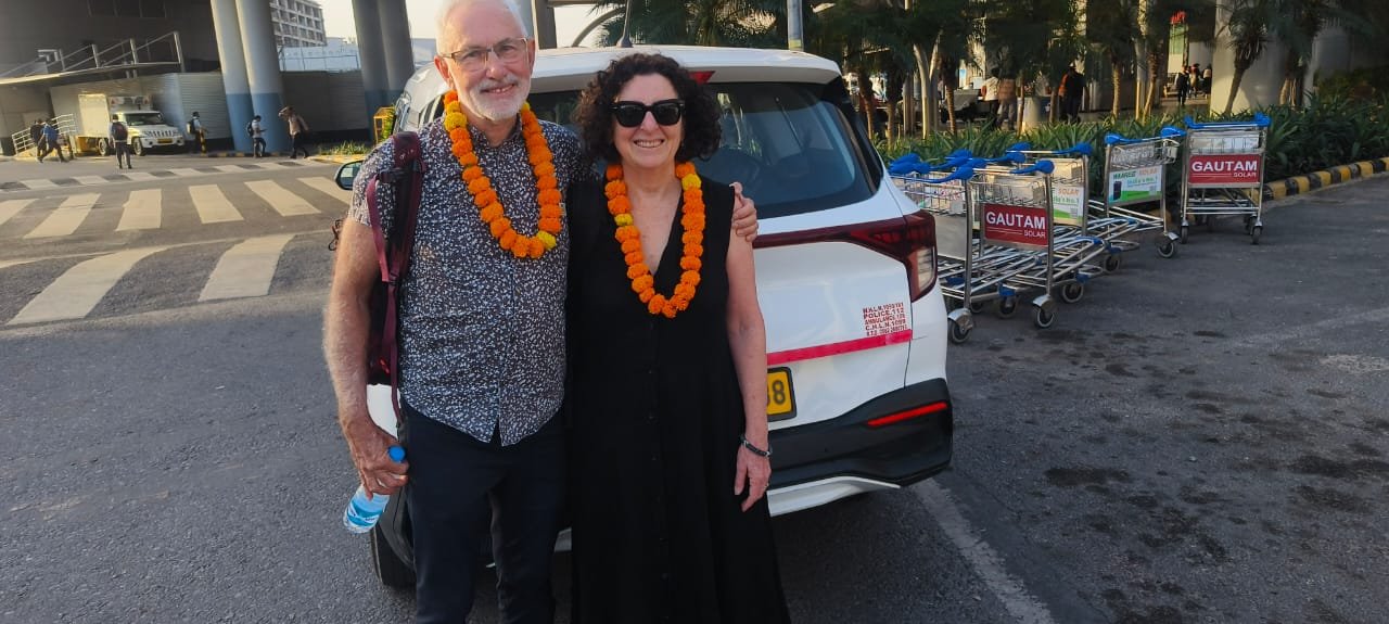 Australian couple arriving at Agra Airport being welcomed by Taj Mahal Cabs driver for airport pickup service in Agra.