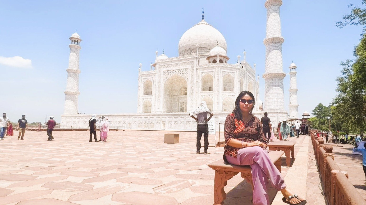 Woman sitting peacefully during a Taj Mahal cultural experience, admiring the Mughal architecture and white marble beauty of the Taj Mahal in Agra at sunrise